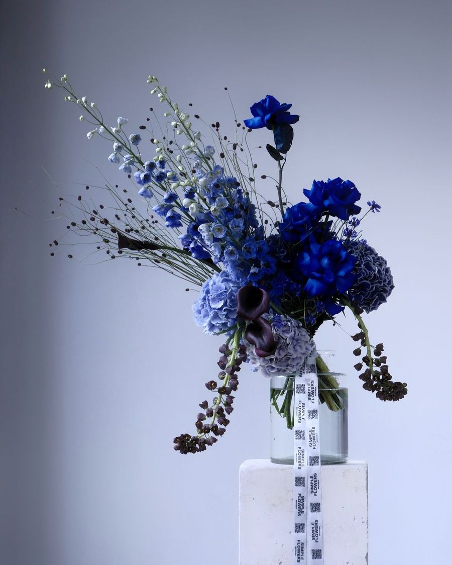 Un ramo de flores azules sobre un pedestal blanco